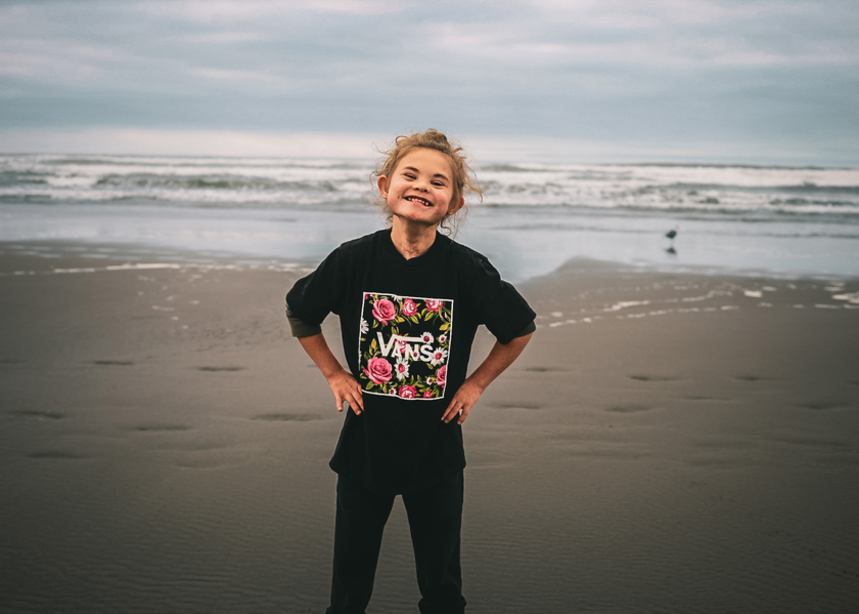 Malachi smiles and poses on the beach.