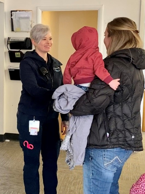  Woman holding baby shakes hand with another woman