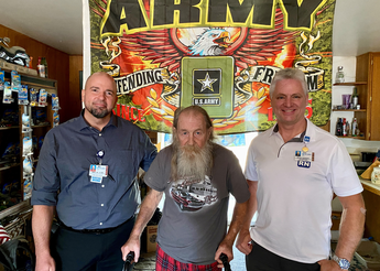 Veteran and Home Health members posing in front of Army flag.