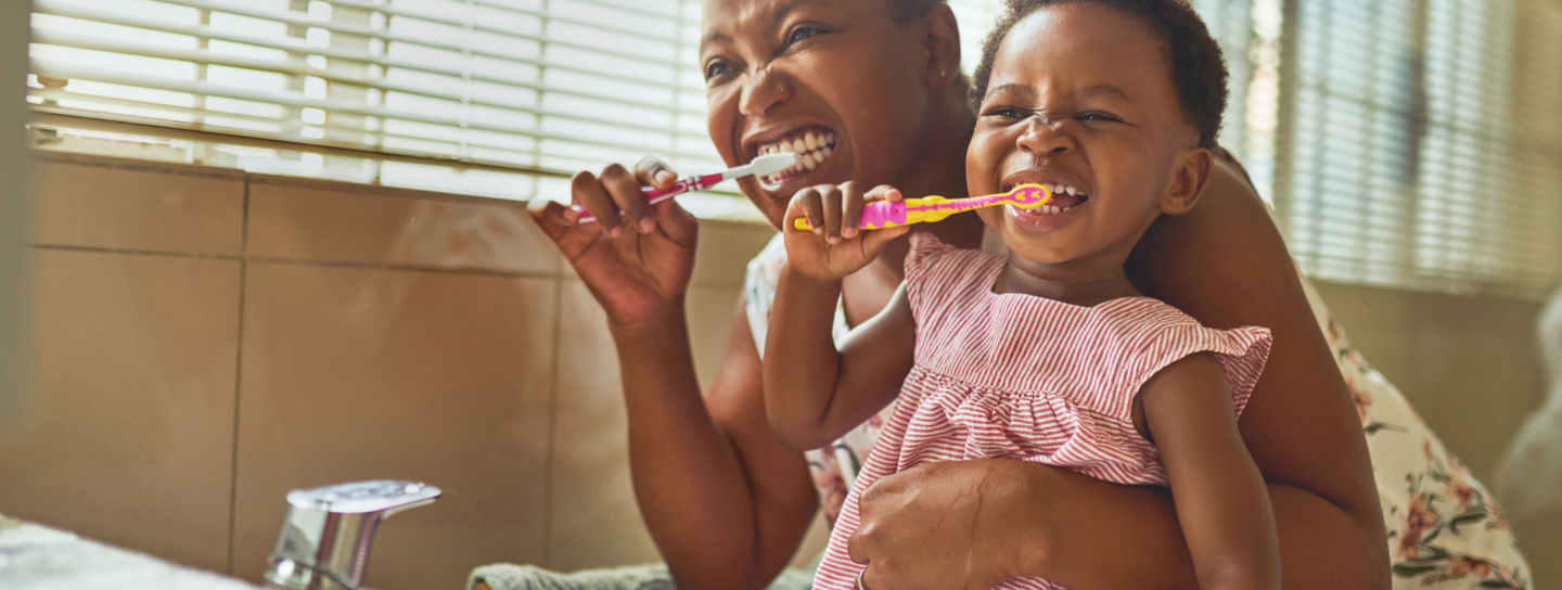 A mom hugs her daughter as they brush their teeth