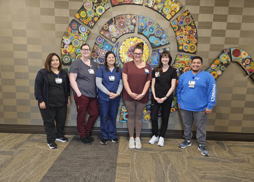 Several people stand in front of a wall with mosaic