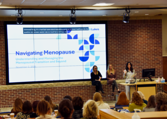 Three women standing in front of an audience.