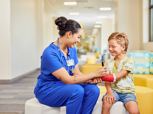 Young boy patient smiles as provider signs his cast.