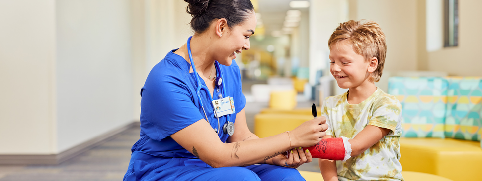 Young boy patient smiles as provider signs his cast.