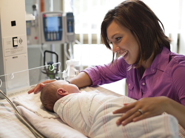 Woman smiles at baby in NICU