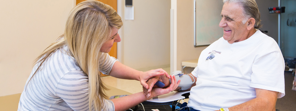 A man sitting in a wheelchair getting checked on by a nurse.