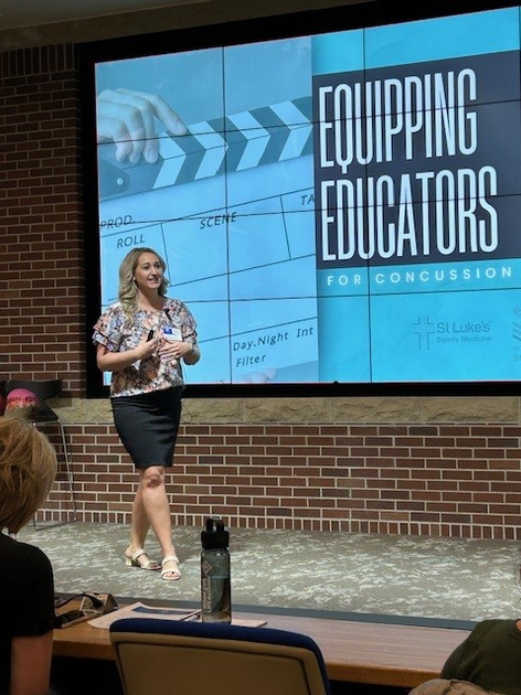 Cassie Luna on stage presenting information to equip educators for concussion.