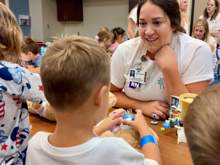  A nurse helps a child work with play medical equipment