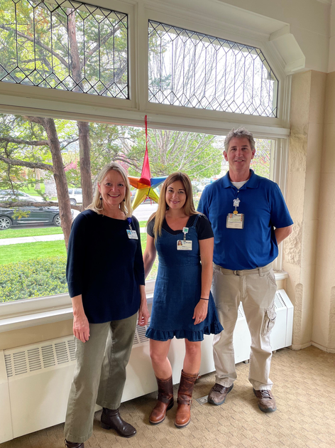  Three people stand in front of a window
