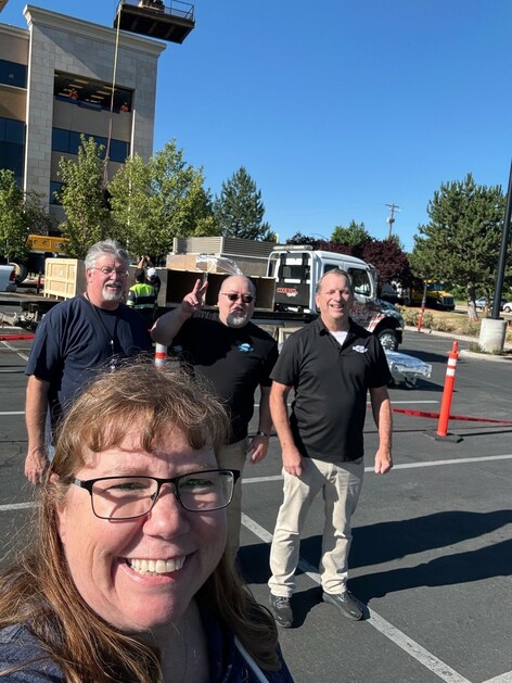 A women pictures with three men in the background all smiling. 