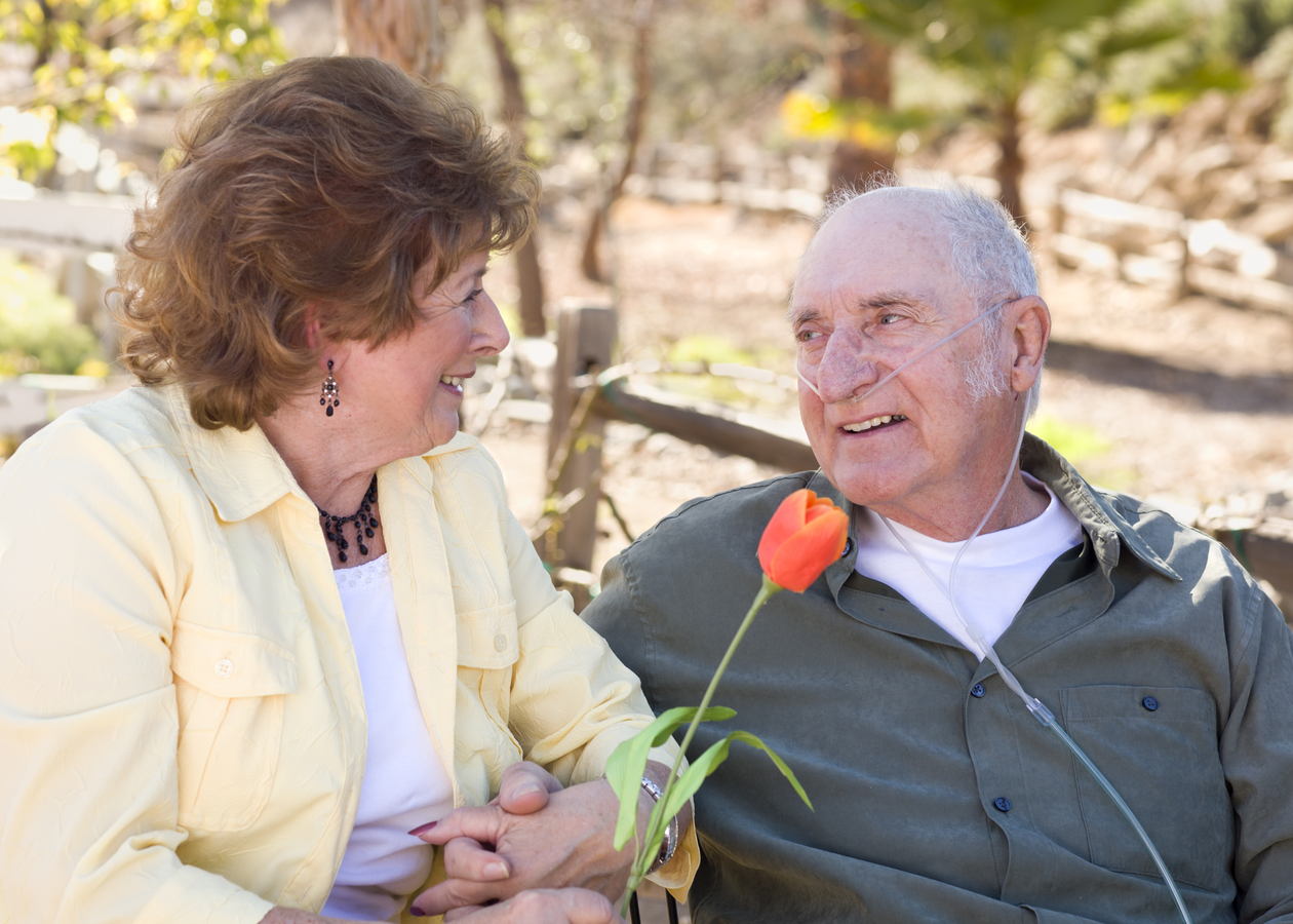 Elderly woman hands an elderly man a flower with a smile