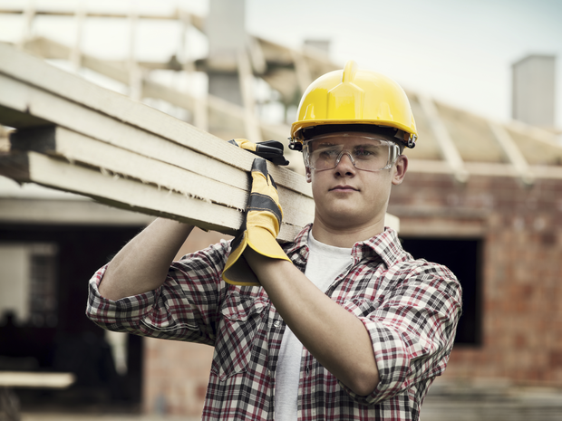 Construction worker carrying boards on shoulder
