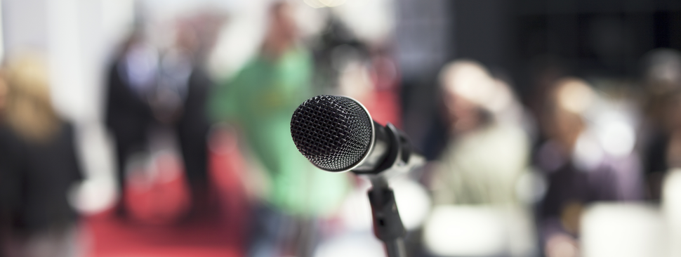 Microphone stand in front of outdoor crowd.