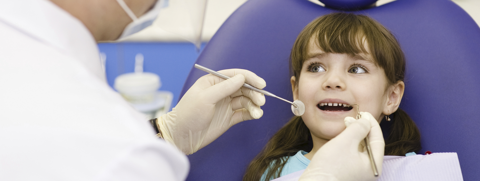 girl smiles while being helped at the dentist