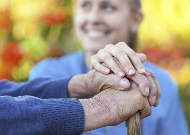 Two hands holding with smiling woman in the background.