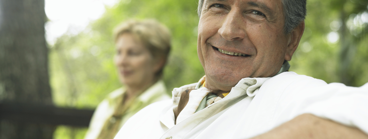 An older man smiles into the camera