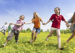 Kids laugh as they run in a grassy field