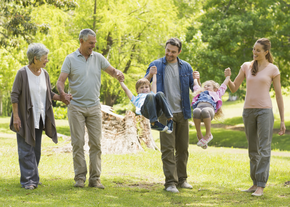 A multigenerational family holds hands, smiling