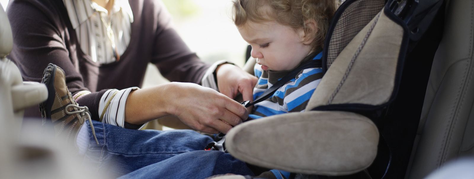 A little boy getting strapped in his carseat.