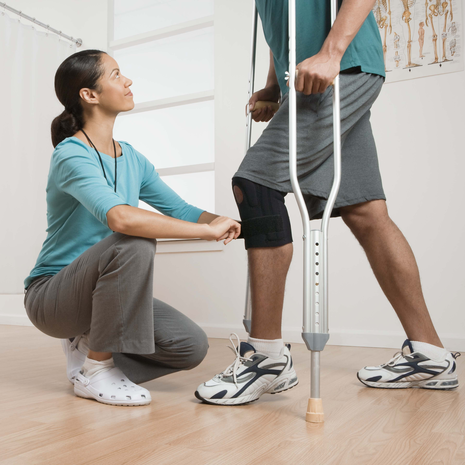 Physical therapist with a patient on crutches with knee brace