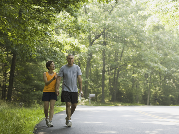 Two adults walk along an outdoor trail while holding hands during the day