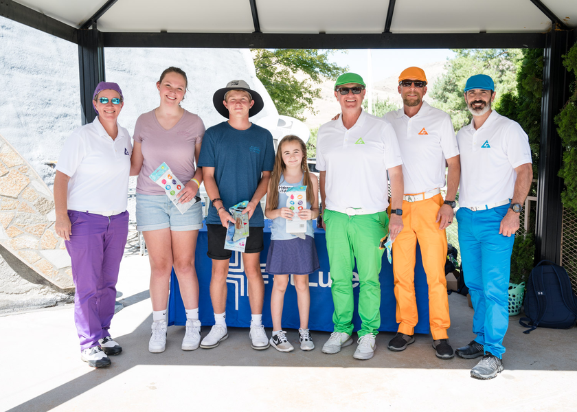 People in bright clothes hold large check