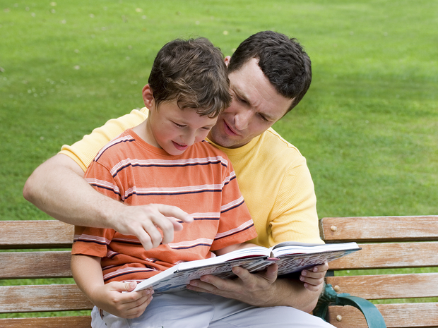 A father reads with his son.