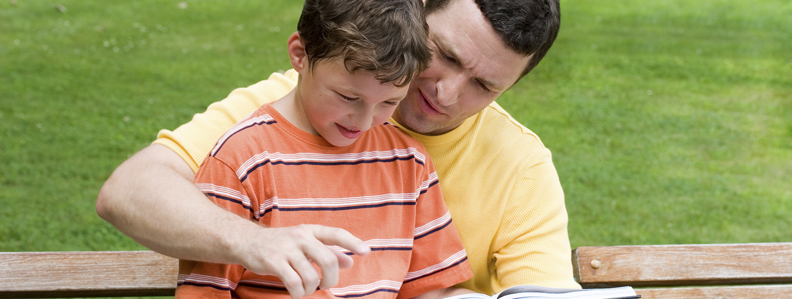A father reads with his son.