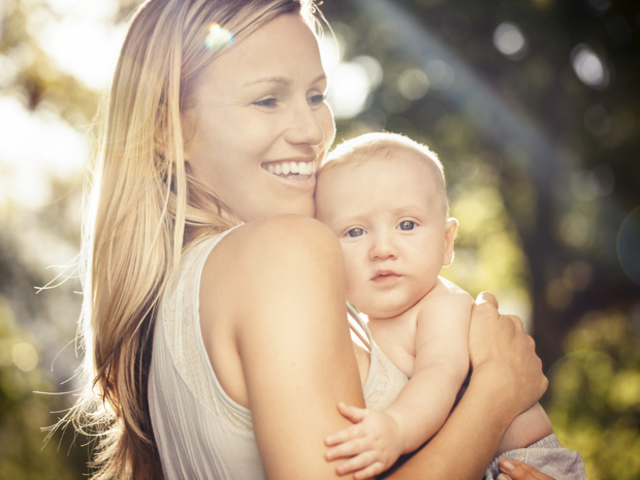 Mother holding baby outdoors.