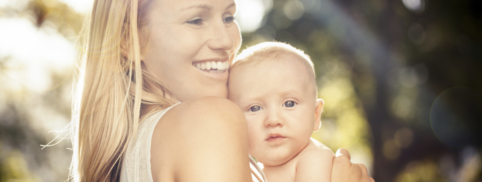 Mother holding baby outdoors.