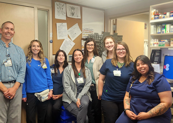Eight pharmacy staff members smile at camera