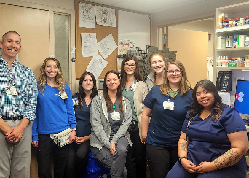 Eight pharmacy staff members smile at camera