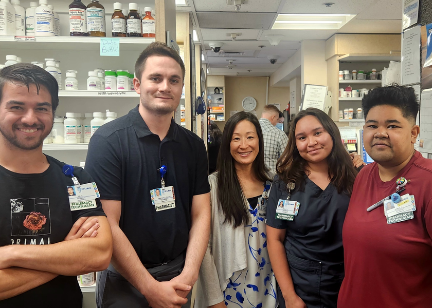  Five people in front of shelves smile at camera