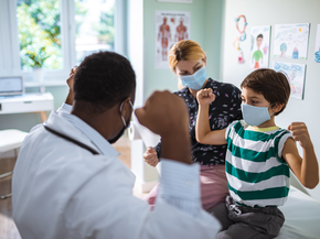 Young patient flexing his muscles with the doctor