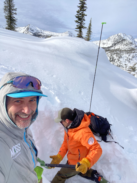 Gary Larson standing in front of a man digging in snow.