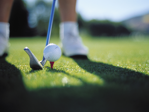 Golf club and ball on tee.