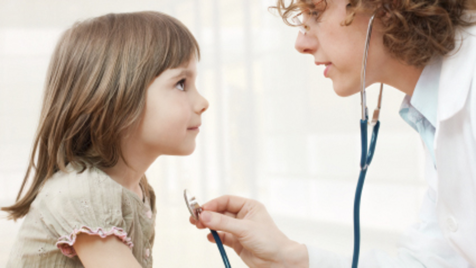 A child being examined by a doctor with a stethescope.