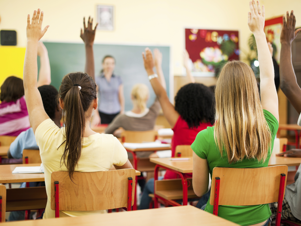 Kids raising their hands in a classroom.