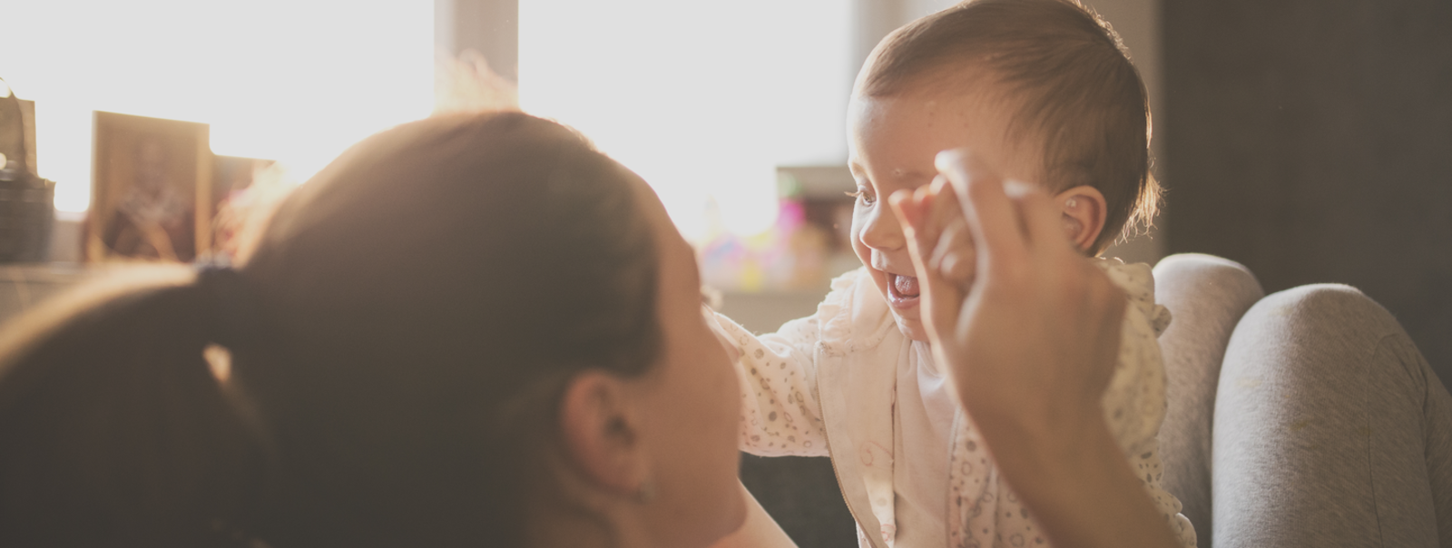 Mom playing with her baby with sunlight in the window.