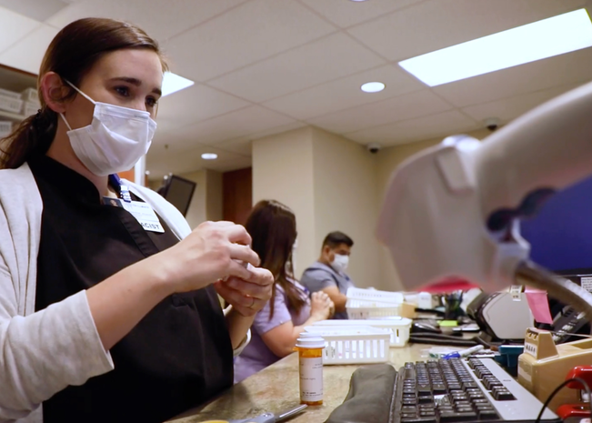 Pharmacy residents in masks work at on-site pharmacy.