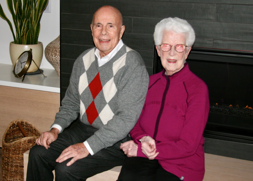 Gail and Jim pose while sitting on a bench at an event.