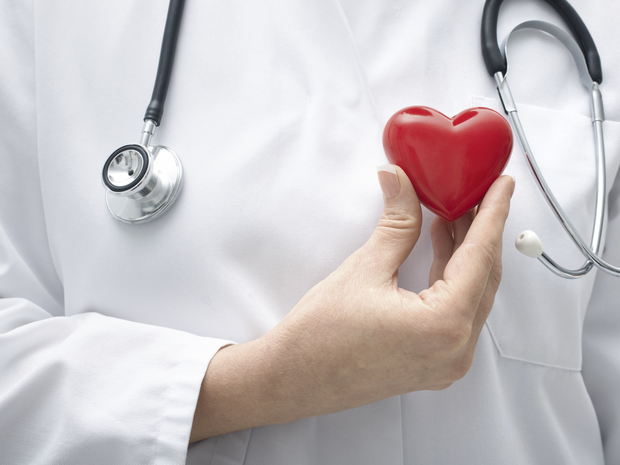 Doctor holding a plastic heart next to a stethoscope.