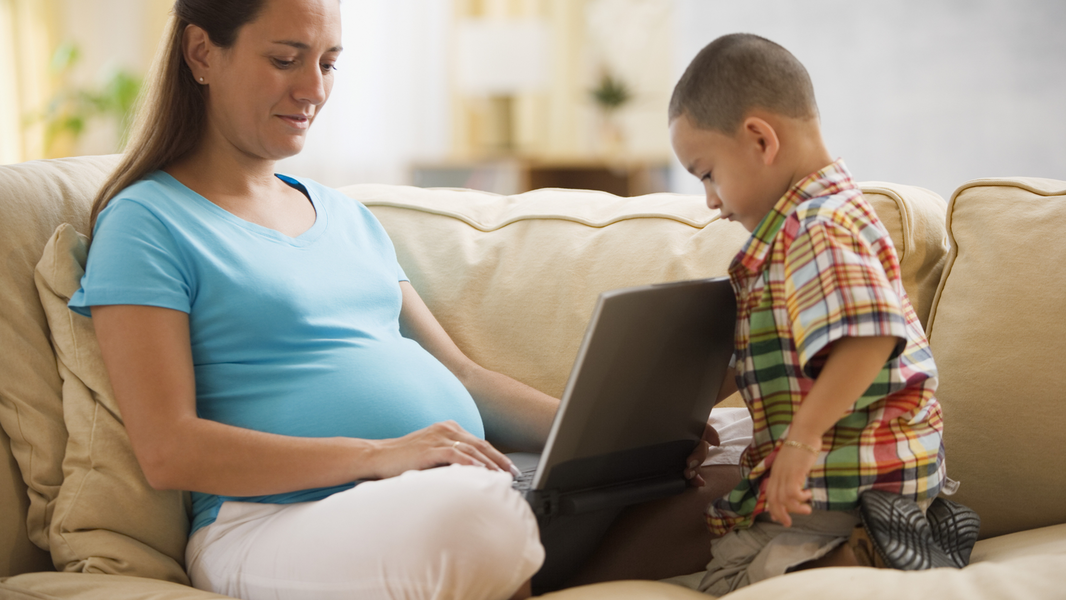 Pregnant mom on laptop with son