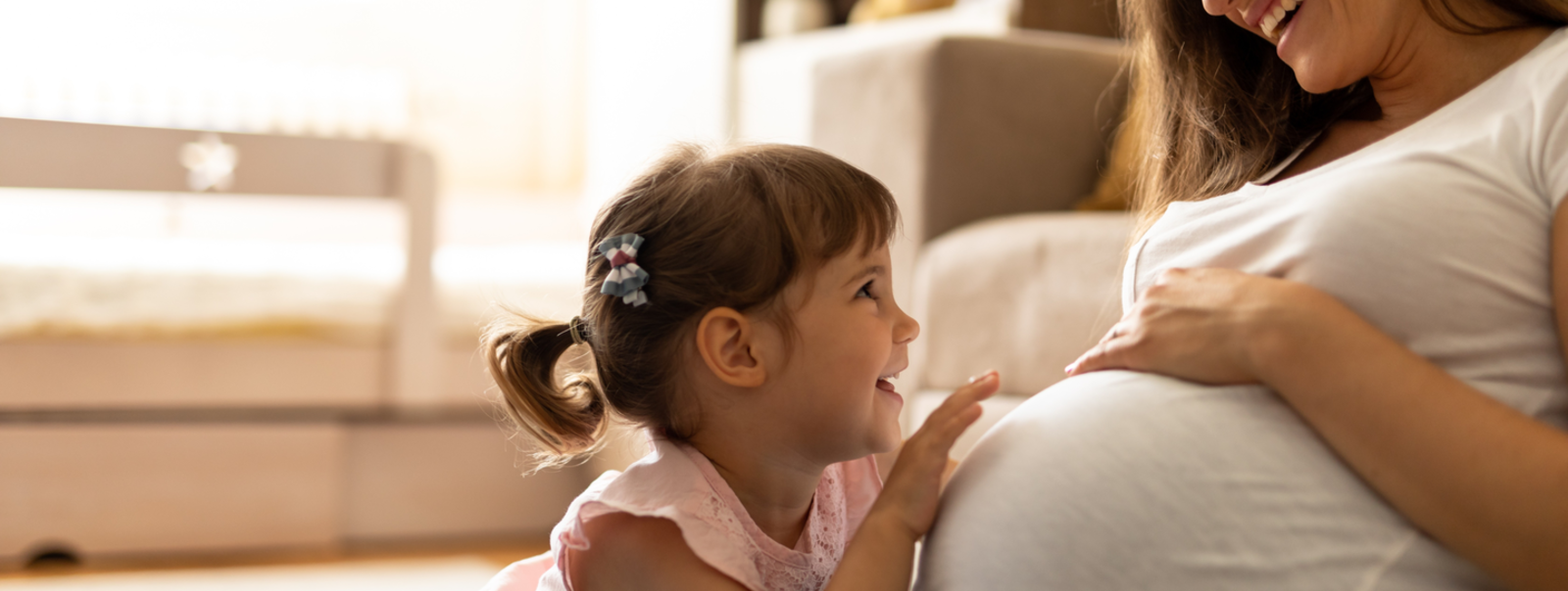 Pregnant mom laughs with toddler.