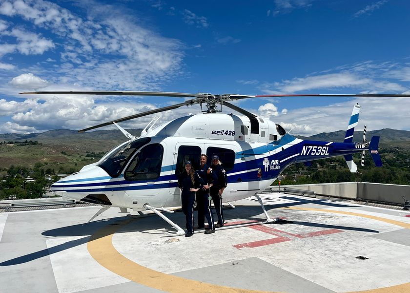 Three women standing outside helicopter