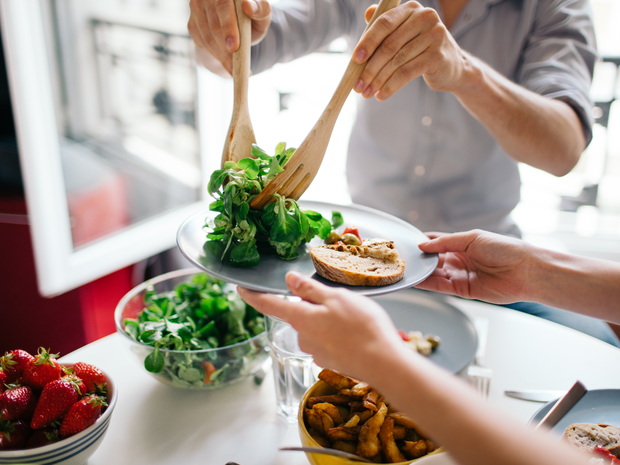 Friends dishing a plate of salad.