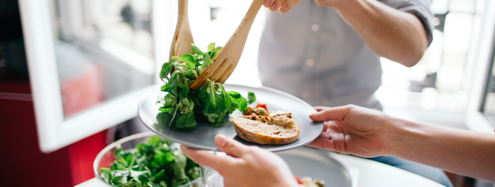 Friends dishing a plate of salad.