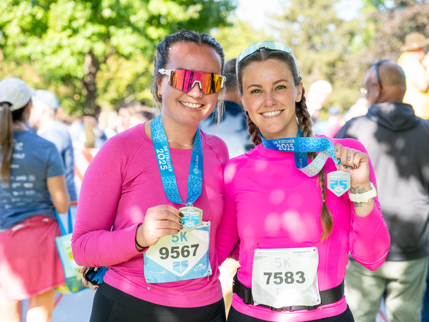 Two women smiling with their FitOne finisher medals