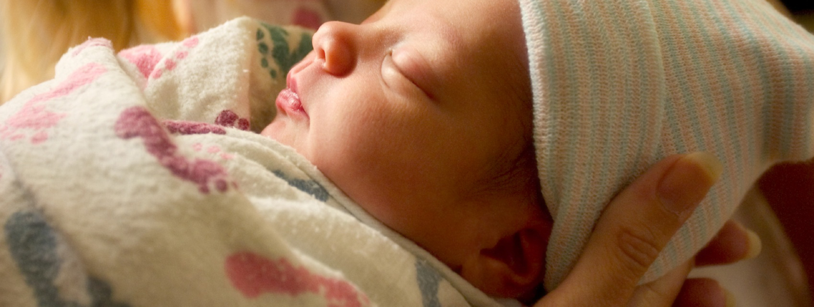 Newborn sleeping as big sister watches.