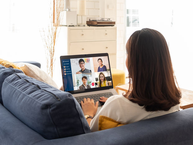 Woman on sofa using laptop for online meeting.